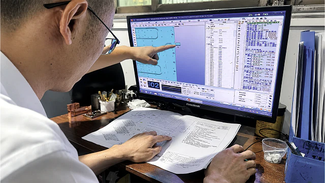 Engineer reviewing CNC dimensions and tolerances against a technical drawing